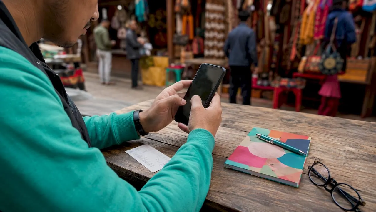 Hands activating LinkedIn Premium on smartphone at café
